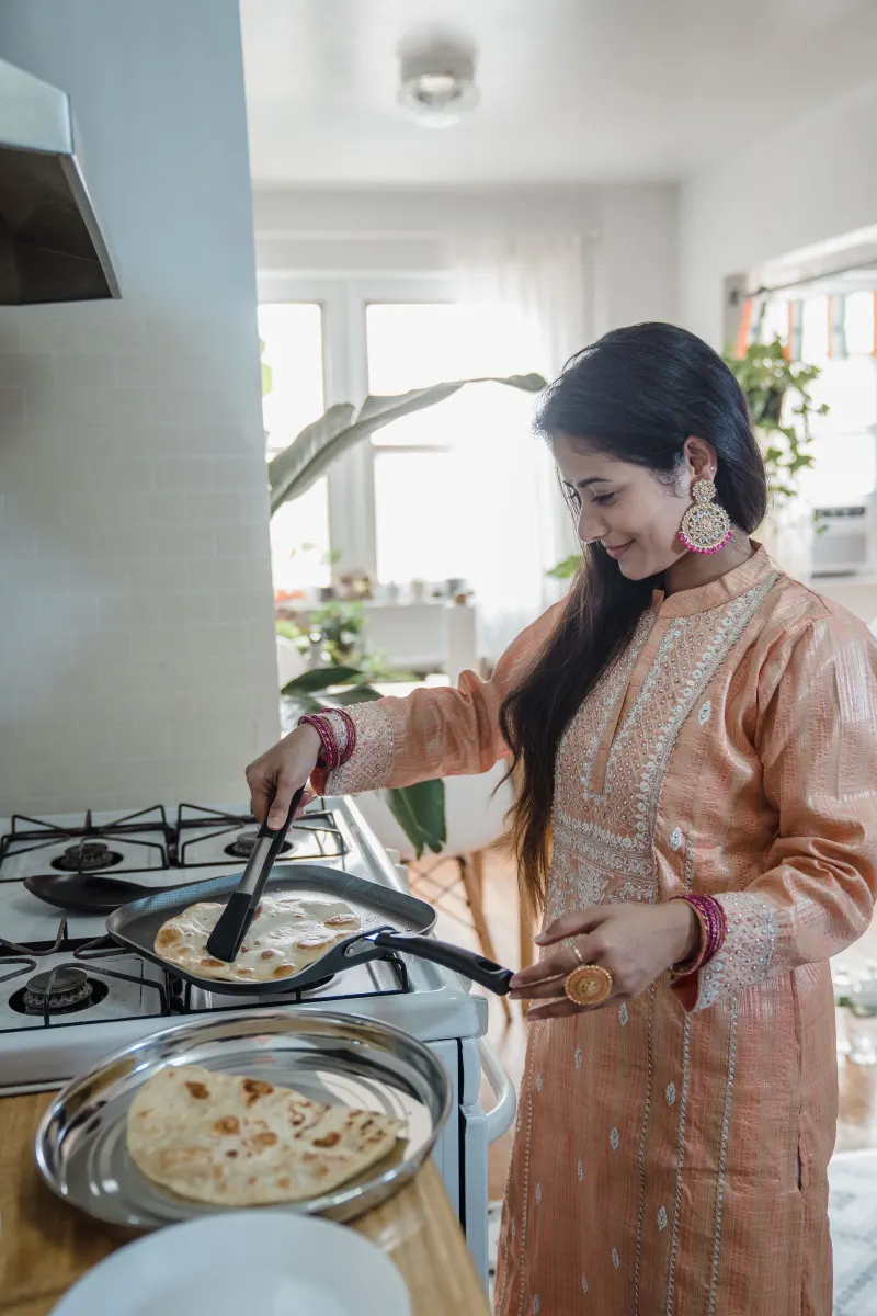 Woman smiling while cooking on a stove in a bright kitchen