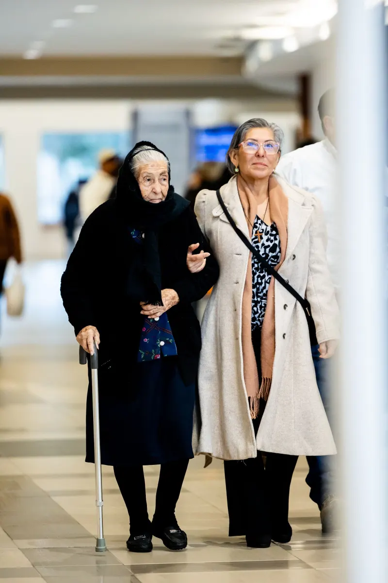 Elderly woman with a cane walking together with a younger woman